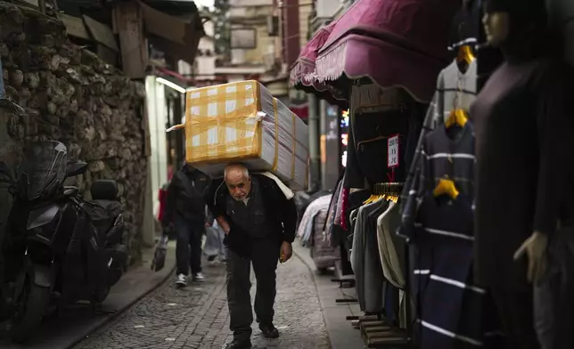 A man carries goods at Eminonu commercial area, in Istanbul, Turkey, Thursday, Dec. 26, 2024 as Turkey's central bank lowered its key interest rate by 2.5 percentage points to 47.5% carrying out its first rate cut in nearly two years as it tries to control soaring inflation. (AP Photo/Francisco Seco)
