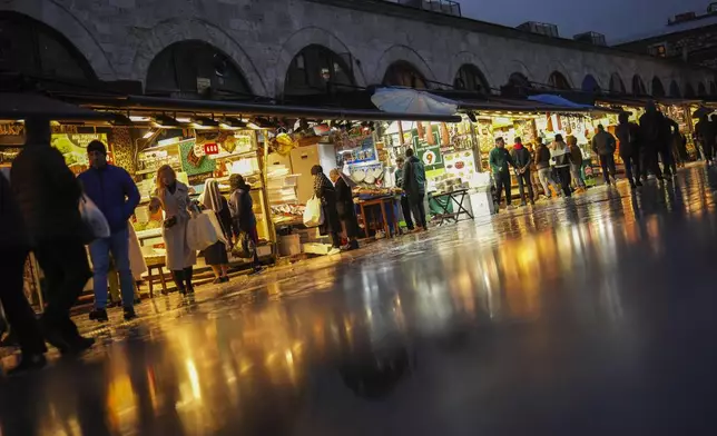 People buy food outside the Egyptian market at Eminonu commercial area, in Istanbul, Turkey, Thursday, Dec. 26, 2024, as Turkey's central bank lowered its key interest rate by 2.5 percentage points to 47.5% carrying out its first rate cut in nearly two years as it tries to control soaring inflation. (AP Photo/Francisco Seco)