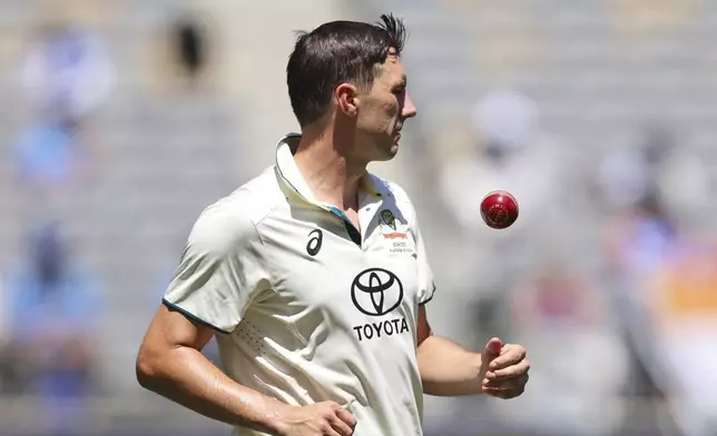 Australia's captain Pat Cummins tosses the ball as he prepares to bowl on the third day of the first cricket test between Australia and India in Perth, Australia, Sunday, Nov. 24, 2024. (AP Photo/Trevor Collens)