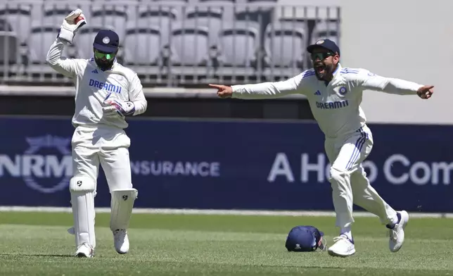 India's Virat Kohli, right, celebrates the wicket of Australia's Travis Head after Rishabh Pant, left, took the catch on the fourth day of the first cricket test between Australia and India in Perth, Australia, Monday, Nov. 25, 2024. (AP Photo/Trevor Collens)