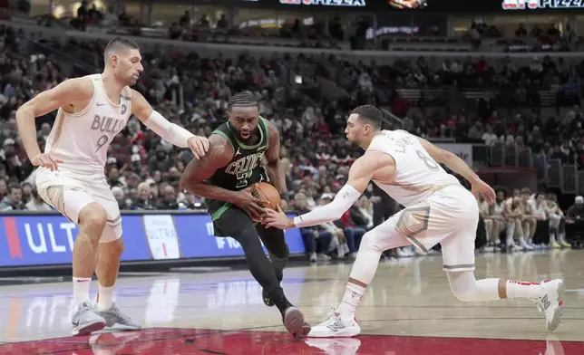 Boston Celtics' Jaylen Brown (7) drives to the basket between Chicago Bulls' Nikola Vucevic (9) and Zach LaVine during the first half of an NBA basketball game Saturday, Dec. 21, 2024, in Chicago. (AP Photo/Charles Rex Arbogast)