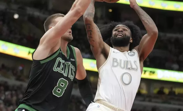 Chicago Bulls' Coby White (0) drives to the basket as Boston Celtics' Kristaps Porzingis defends during the second half of an NBA basketball game Saturday, Dec. 21, 2024, in Chicago. (AP Photo/Charles Rex Arbogast)