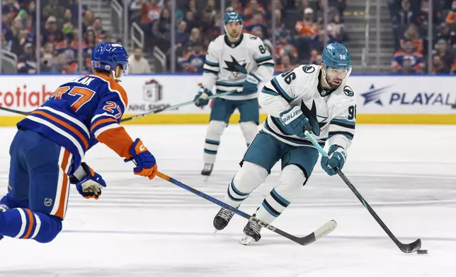 San Jose Sharks' Jake Walman (96) skates with the puck against Edmonton Oilers' Brett Kulak (27) during the first period of an NHL hockey game in Edmonton, Alberta, Saturday, Dec. 21, 2024. (Timothy Matwey/The Canadian Press via AP)