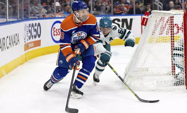 Edmonton Oilers' Zach Hyman (18) skates with the puck against San Jose Sharks' Mikael Granlund (64) during second-period NHL hockey game action in Edmonton, Alberta, Saturday, Dec. 21, 2024. (Timothy Matwey/The Canadian Press via AP)