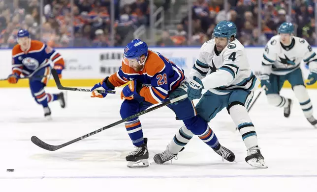 Edmonton Oilers' Connor Brown (28) battles for the puck against San Jose Sharks' Cody Ceci (4) during the second period of an NHL hockey game in Edmonton, Alberta, Saturday, Dec. 21, 2024. (Timothy Matwey/The Canadian Press via AP)