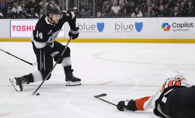 Los Angeles Kings right wing Alex Laferriere (14) looks to shoot the puck while Philadelphia Flyers right wing Bobby Brink (10) defends during the second period of an NHL hockey game, Sunday, Dec. 29, 2024, in Los Angeles. (AP Photo/William Liang)