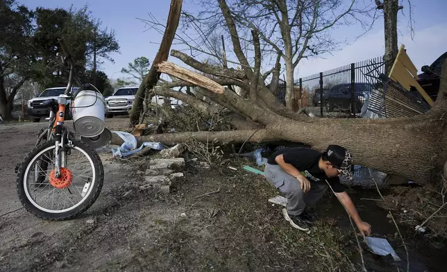 J.C. Betanzos, 11, looks for items from his sister's business and things his deceased mother gave them that blew away during a tornado, Saturday, Dec. 28, 2024, in Katy, Texas. (Elizabeth Conley/Houston Chronicle via AP)