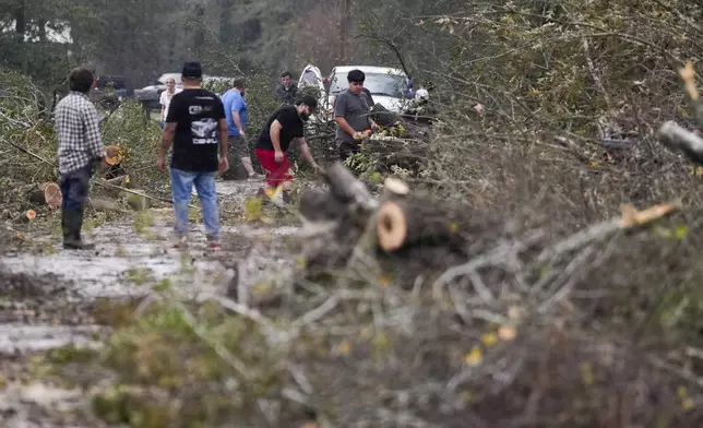 People remove debris from a street after strong thunderstorms pass through the Greater Houston region, Saturday, Dec. 28, 2024, in Porter Heights. (Jason Fochtman/Houston Chronicle via AP)