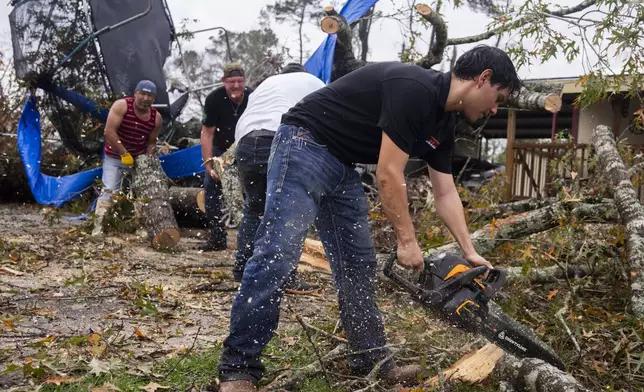 Ricardo Rodriguez uses a chain saw to remove debris from a woman's home after strong thunderstorms pass through the Greater Houston region, Saturday, Dec. 28, 2024, in Porter Heights. (Jason Fochtman/Houston Chronicle via AP)