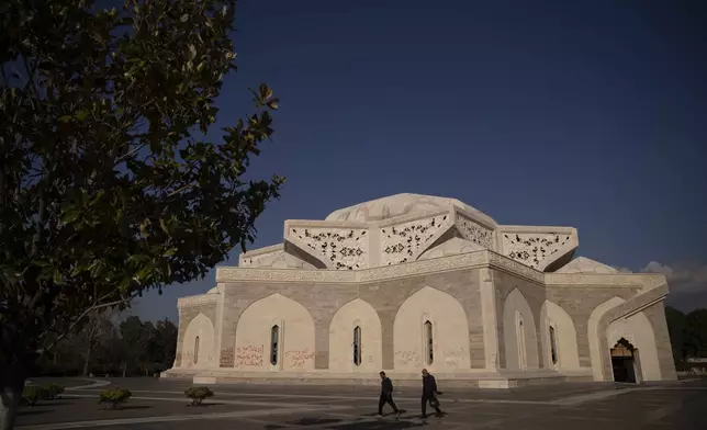 People walk by the mausoleum of Syria's former President Hafez Assad in Qardaha, Syria, on Tuesday, Dec. 17, 2024. (AP Photo/Leo Correa)