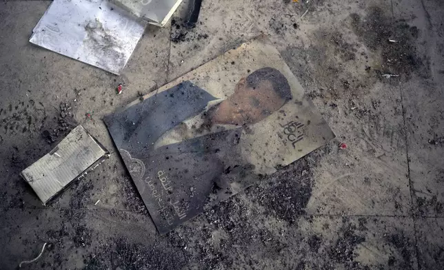 A photo of ousted Syrian President Bashar Assad lies on the ground of his family's damaged property in Qardaha, Syria, on Tuesday, Dec. 17, 2024. (AP Photo/Leo Correa)