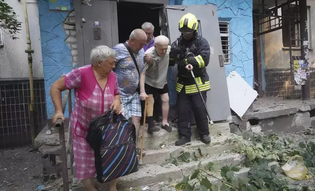 Rescuers help elderly residents to leave their damaged home after Russia's guided air bomb hit an apartment building in Kharkiv, Ukraine, Friday, Aug. 30, 2024. (AP Photo/Andrii Marienko)