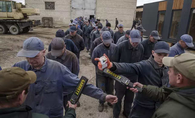 Security guards search captured Russian soldiers with a metal detector at the prisoner of war detention center in Ukraine's Lviv region, Thursday, April 25, 2024. (AP Photo/Evgeniy Maloletka)