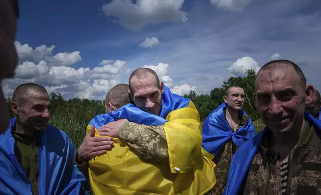 A Ukrainian serviceman hugs his comrade after returning from captivity during a POWs exchange in Sumy region, Ukraine, Friday, May 31, 2024. (AP Photo/Evgeniy Maloletka)