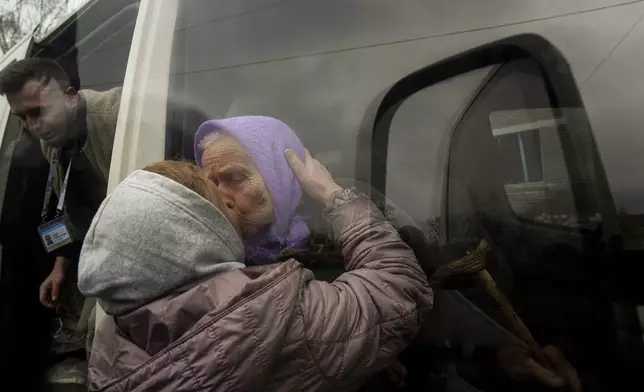 Olha Faichuk, 79, kisses her neighbor as she is evacuated from her home, which was heavily damaged by a Russian airstrike in Lukiantsi, Kharkiv region, Ukraine, on Tuesday, April 16, 2024. (AP Photo/Evgeniy Maloletka)