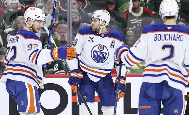Edmonton Oilers center Leon Draisaitl, center, is congratulated for his goal against the Minnesota Wild during the second period of an NHL hockey game Thursday, Dec. 12, 2024, in St. Paul, Minn. (AP Photo/Matt Krohn)