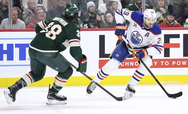 Edmonton Oilers center Leon Draisaitl, right, skates with the puck as Minnesota Wild right wing Ryan Hartman (38) defends during the second period of an NHL hockey game Thursday, Dec. 12, 2024, in St. Paul, Minn. (AP Photo/Matt Krohn)