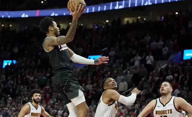 Portland Trail Blazers guard Anfernee Simons, top, shoots a game-winning basket over Denver Nuggets guard Russell Westbrook, center, and center Nikola Jokic (15) during the second half of an NBA basketball game in Portland, Ore., Thursday, Dec. 19, 2024. (AP Photo/Craig Mitchelldyer)