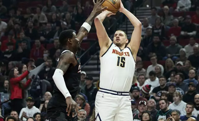 Denver Nuggets center Nikola Jokic, right, shoots a 3-point basket over Portland Trail Blazers center Deandre Ayton during the first half of an NBA basketball game in Portland, Ore., Thursday, Dec. 19, 2024. (AP Photo/Craig Mitchelldyer)