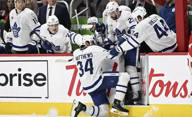 Toronto Maple Leafs center Auston Matthews (34) gets pulled off the ice by his teammates on the bench after losing the blade on his right skate against the Detroit Red Wings during the second period of an NHL hockey game, Saturday, Dec. 14, 2024 in Detroit. (AP Photo/Lon Horwedel)