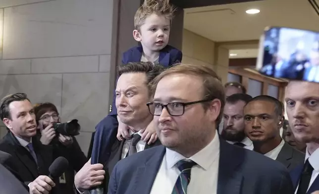 Elon Musk, center, carrying his son X Æ A-Xii, arrives for a roundtable meeting to discuss President-elect Donald Trump's planned Department of Government Efficiency, Thursday, Dec. 5, 2024, on Capitol Hill in Washington. (AP Photo/Mariam Zuhaib)