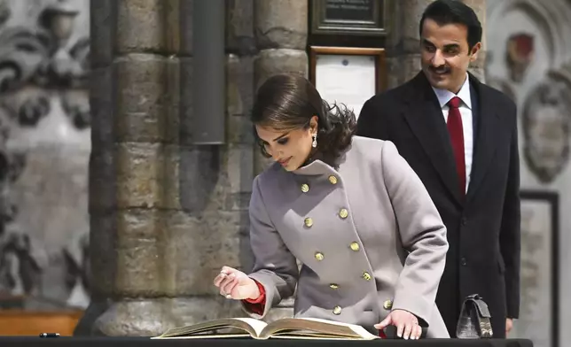 Qatar's Emir Sheikh Tamim bin Hamad al-Thani looks as his wife Sheikha Jawaher bint Hamad bin Suhaim al-Thani signing the guests book during a visit to Westminster Abbey, in London, Tuesday, Dec. 3, 2024, on the first day of their two-day State Visit to Britain. ( Justin Tallis/Pool photo via AP)