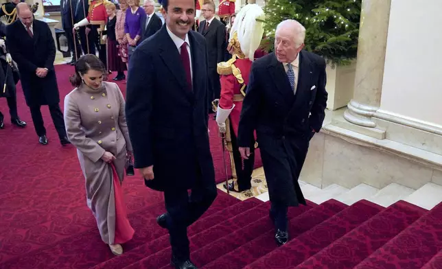 Britain's King Charles III, right, and Britain's Queen Camilla, behind Qatar's Emir, walk with the Emir of Qatar Sheikh Tamim bin Hamad Al Thani, foreground left, and his wife Sheikha Jawaher during the state visit to the UK of the Emir of Qatar, in London, Tuesday, Dec. 3, 2024. (Jonathan Brady via AP, Pool)