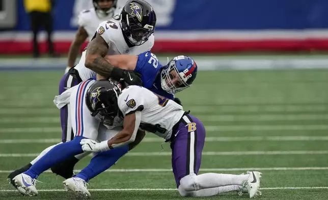 Baltimore Ravens linebacker Chris Board (49) and cornerback Marlon Humphrey (44) tackle New York Giants tight end Daniel Bellinger (82) during the third quarter of an NFL football game, Sunday, Dec. 15, 2024, in East Rutherford, N.J. (AP Photo/Seth Wenig)