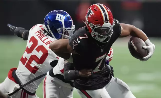 Atlanta Falcons running back Bijan Robinson (7) runs the ball against New York Giants cornerbacks Cor'Dale Flott (28) and Dru Phillips (22) in the second half of an NFL football game in Atlanta, Sunday, Dec. 22, 2024. (AP Photo/Mike Stewart)