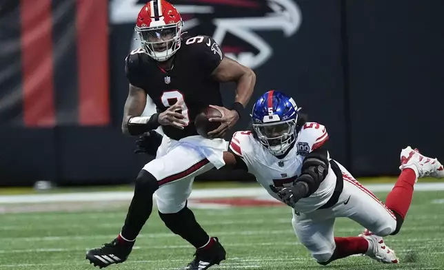 Atlanta Falcons quarterback Michael Penix Jr. (9) tackled by New York Giants linebacker Kayvon Thibodeaux (5) short of the first down in the first half of an NFL football game in Atlanta, Sunday, Dec. 22, 2024. (AP Photo/John Bazemore)