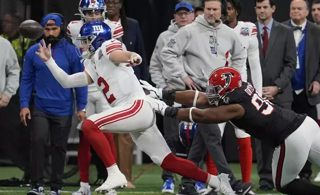 New York Giants quarterback Drew Lock (2) is knocked out of bounds by Atlanta Falcons defensive tackle David Onyemata (90) in the first half of an NFL football game in Atlanta, Sunday, Dec. 22, 2024. (AP Photo/Mike Stewart)