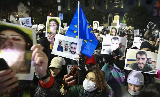 Demonstrators hold portraits of activists injured during protests as they take part in an anti-government rally outside the Parliament building in Tbilisi, Georgia, on Saturday, Dec. 14, 2024. (AP Photo/Zurab Tsertsvadze)