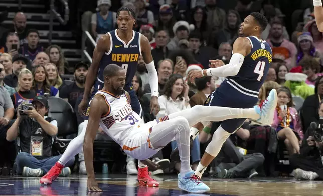 Phoenix Suns forward Kevin Durant falls to the floor after getting fouled by Denver Nuggets guard Russell Westbrook during the first half of an NBA basketball game, Wednesday, Dec. 25, 2024, in Phoenix. (AP Photo/Rick Scuteri)