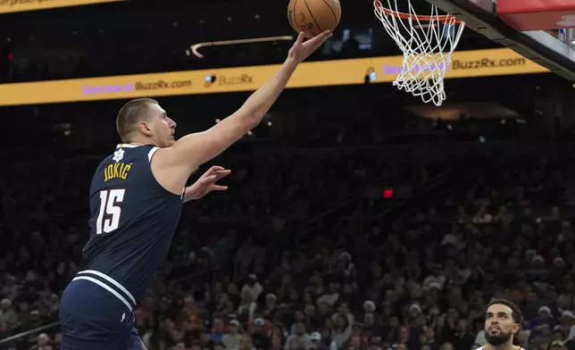 Denver Nuggets center Nikola Jokic scores on Phoenix Suns guard Tyus Jones during the first half of an NBA basketball game, Wednesday, Dec. 25, 2024, in Phoenix. (AP Photo/Rick Scuteri)