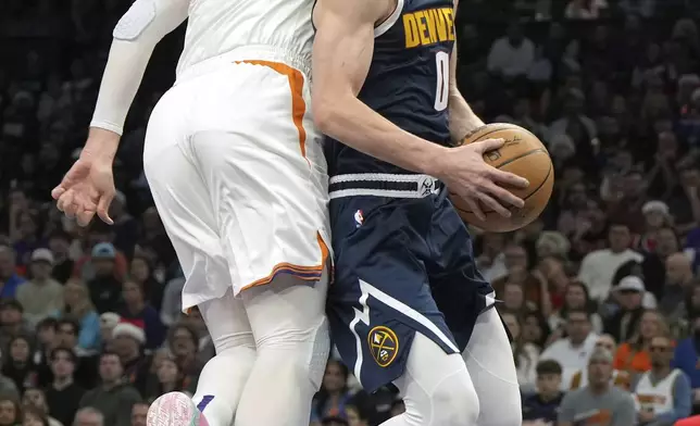 Denver Nuggets guard Christian Braun gets fouled by Phoenix Suns center Jusuf Nurkic (20) during the first half of an NBA basketball game, Wednesday, Dec. 25, 2024, in Phoenix. (AP Photo/Rick Scuteri)