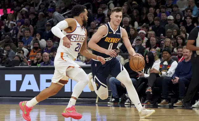 Denver Nuggets guard Christian Braun drives on Phoenix Suns guard Tyus Jones during the first half of an NBA basketball game, Wednesday, Dec. 25, 2024, in Phoenix. (AP Photo/Rick Scuteri)