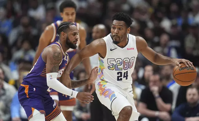 Denver Nuggets guard Jalen Pickett, right, drives past Phoenix Suns guard Monte Morris in the second half of an NBA basketball game Monday, Dec. 23, 2024, in Denver. (AP Photo/David Zalubowski)