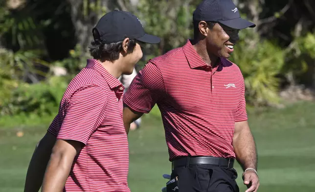 Tiger Woods, right, congratulates his son Charlie Woods after his hole-in-one on the fourth hole during the final round of the PNC Championship golf tournament, Sunday, Dec. 22, 2024, in Orlando, Fla. (AP Photo/Phelan M. Ebenhack)