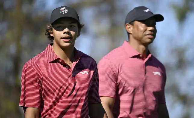 Charlie Woods, left, walks on the fourth fairway after hitting a hole-in-on as his father Tiger Woods follows during the final round of the PNC Championship golf tournament, Sunday, Dec. 22, 2024, in Orlando, Fla. (AP Photo/Phelan M. Ebenhack)