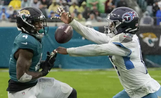 Tennessee Titans linebacker Jerome Baker, right, breaks up a pass intended for Jacksonville Jaguars running back Tank Bigsby (4) during the first half of an NFL football game Sunday, Dec. 29, 2024, in Jacksonville, Fla. (AP Photo/John Raoux)