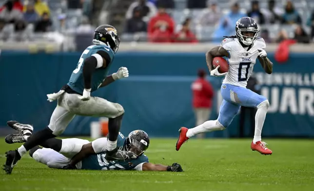 Tennessee Titans wide receiver Calvin Ridley (0) runs the ball past Jacksonville Jaguars defensive end Myles Cole, center, and safety Andre Cisco (5) during the second half of an NFL football game Sunday, Dec. 29, 2024, in Jacksonville, Fla. (AP Photo/Phelan M. Ebenhack)