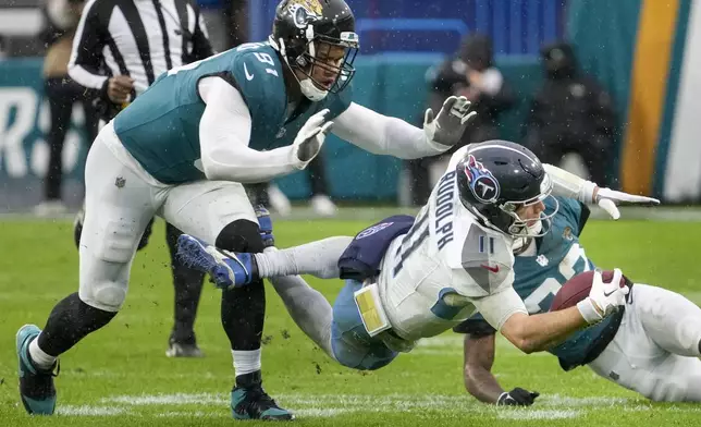 Tennessee Titans quarterback Mason Rudolph (11) dives for extra yards past Jacksonville Jaguars defensive end Arik Armstead (91) during the first half of an NFL football game Sunday, Dec. 29, 2024, in Jacksonville, Fla. (AP Photo/John Raoux)