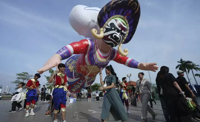 A giant balloon depicting a dancer flies over the people before a performance during the "Celebrating Cambodia" event as part of the New Year's Eve in front of Royal Palace in Phnom Penh, Cambodia, Tuesday Dec. 31, 2024. (AP Photo/Heng Sinith)