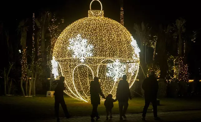 Egyptians walk in front of New Year decorations in Cairo, Egypt, Tuesday, Dec. 31, 2024. (AP Photo/Amr Nabil)