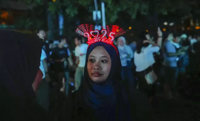 A woman wears a 2025 headband in the main business district on New Year's Eve in Jakarta, Indonesia, Tuesday, Dec. 31, 2024. (AP Photo/Tatan Syuflana)