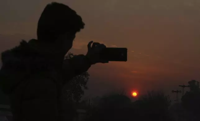 A Pakistani man take a selfie photo while the last sunset of 2024 hangs over the city of Peshawar, Pakistan, Tuesday, Dec. 31, 2024. (AP Photo/Mohammad Sajjad)