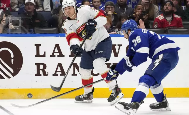 Florida Panthers center Sam Reinhart (13) shoots in front of Tampa Bay Lightning center Zemgus Girgensons (28) during the first period of an NHL hockey game Sunday, Dec. 22, 2024, in Tampa, Fla. (AP Photo/Chris O'Meara)