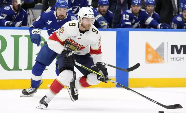 Florida Panthers center Sam Bennett (9) carries the puck past Tampa Bay Lightning left wing Nick Paul (20) during the first period of an NHL hockey game Sunday, Dec. 22, 2024, in Tampa, Fla. (AP Photo/Chris O'Meara)