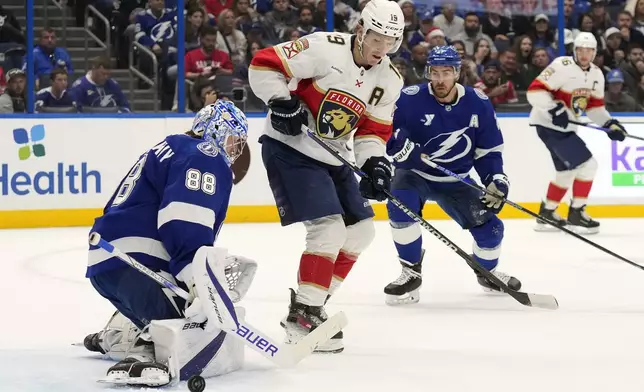 Tampa Bay Lightning goaltender Andrei Vasilevskiy (88) makes a pad-save on a deflection by Florida Panthers left wing Matthew Tkachuk (19) during the first period of an NHL hockey game Sunday, Dec. 22, 2024, in Tampa, Fla. (AP Photo/Chris O'Meara)