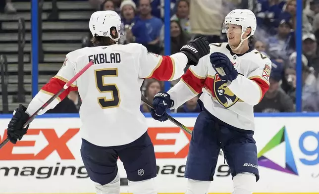 Florida Panthers center Eetu Luostarinen, right, celebrates after his goal against the Tampa Bay Lightning with defenseman Aaron Ekblad (5) during the second period of an NHL hockey game Sunday, Dec. 22, 2024, in Tampa, Fla. (AP Photo/Chris O'Meara)